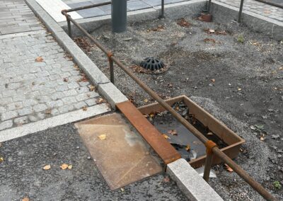 Regnbädd under anläggning med monterat regnbäddsinlopp och räcke intill stenläggningsyta.